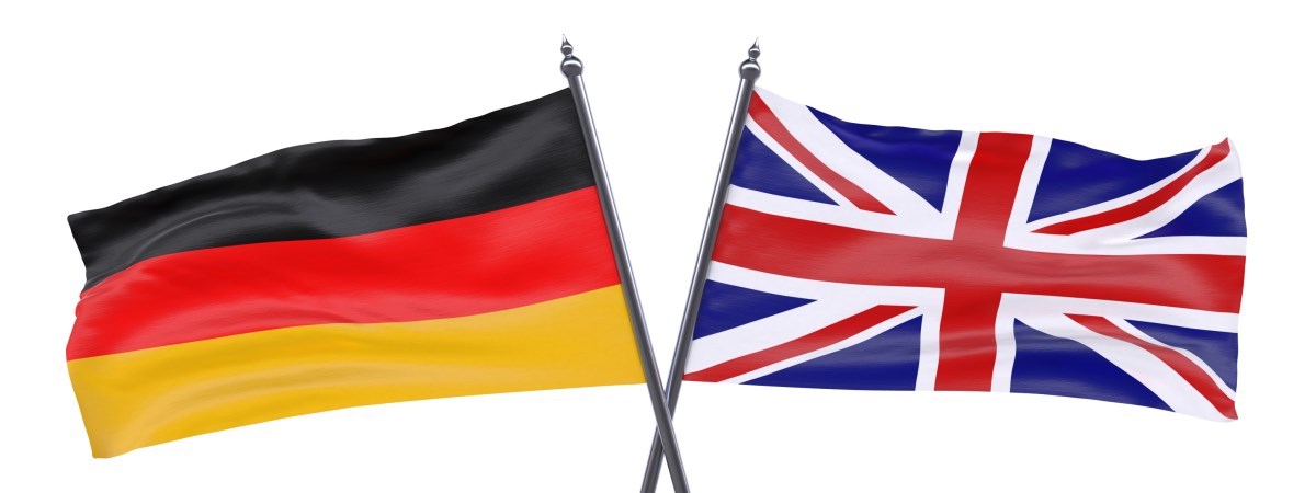 Eine britische Flagge und eine deutsche Flagge. Die Fahnenhalterungen kreuzen sich.