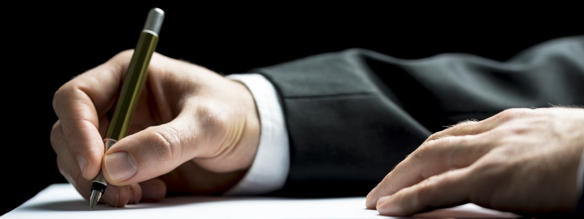 Man in suit signs a document.